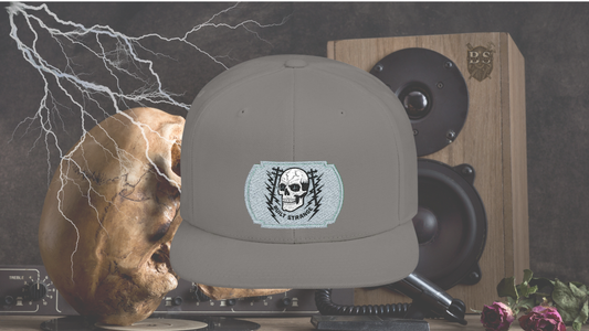 Shock, grit, and street-ready energy.
The Built Strange Skull & Power Lines Snapback Hat features a bold embroidered-style patch: a grinning skull with electric-blue eyes, flanked by utility poles and jagged lightning bolts. This design embodies the raw power and fearless pride of the trade, making it more than just a hat—it’s a statement.
Built on a structured snapback silhouette, it’s equal parts workwear toughness and streetwear edge.
